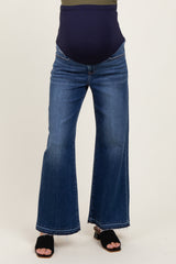 maternity wear blue flared jeans with a over-the-bump waistband, model wearing black sandals and a dark top
