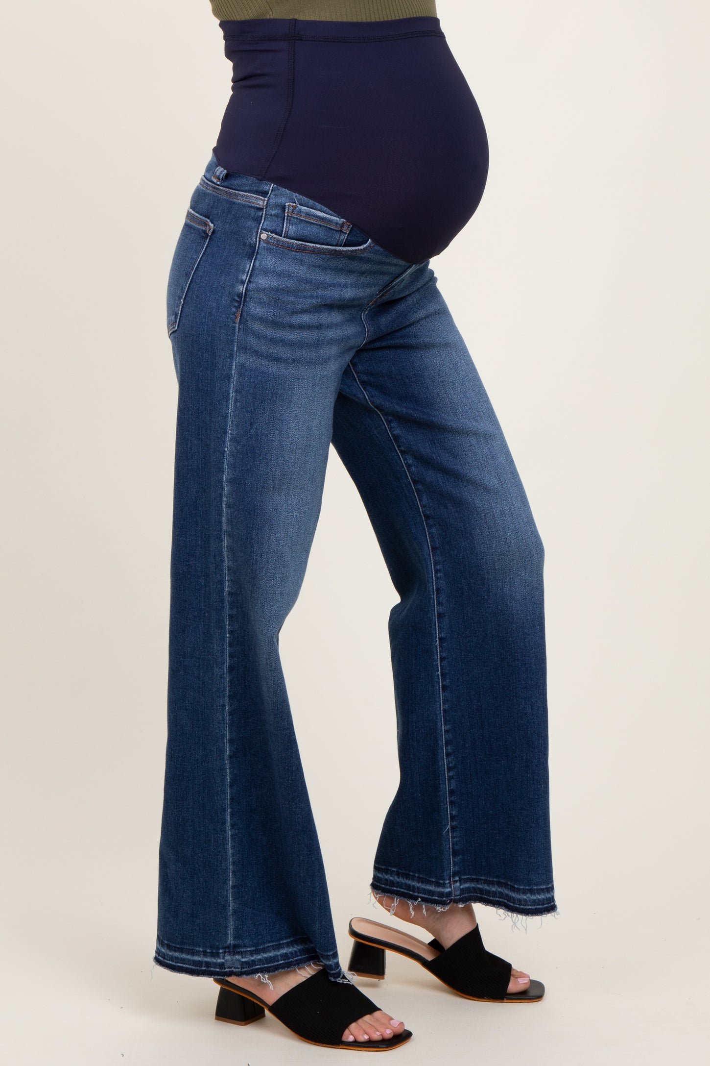 woman wearing a navy blue maternity belly support jeans with wide legs and a pregnant baby bump visible