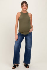 woman wearing an olive green ribbed maternity tank top and blue wide-leg maternity jeans, showing her baby bump