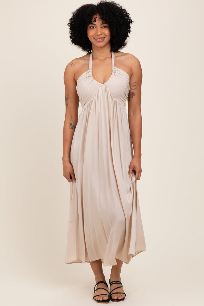 woman wearing a beige halter neck maxi dress with gathered detailing and slim straps
