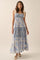 woman wearing a floral blue and cream maxi dress with tie straps and a tiered skirt