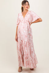 woman wearing a pink floral maternity maxi dress with flutter sleeves and a tiered skirt, showcasing her baby bump