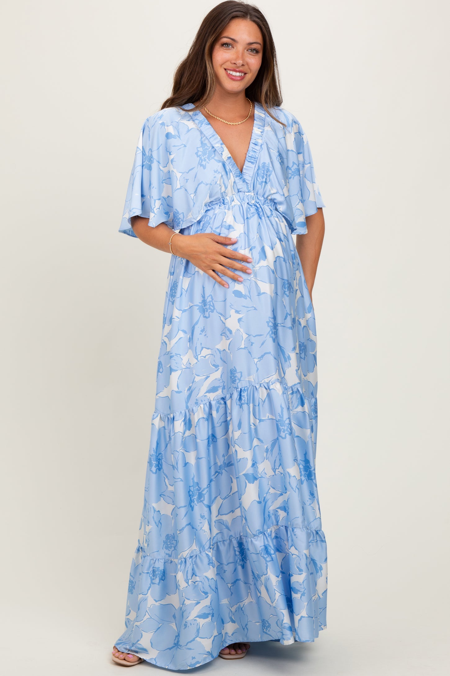 woman wearing a light blue floral maternity maxi dress and holding her baby bump