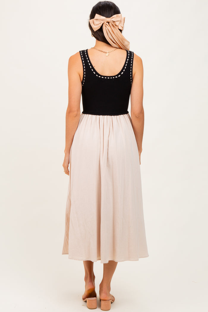 woman wearing a black knitted tank top and a light beige flowy midi skirt, with her back turned to the camera