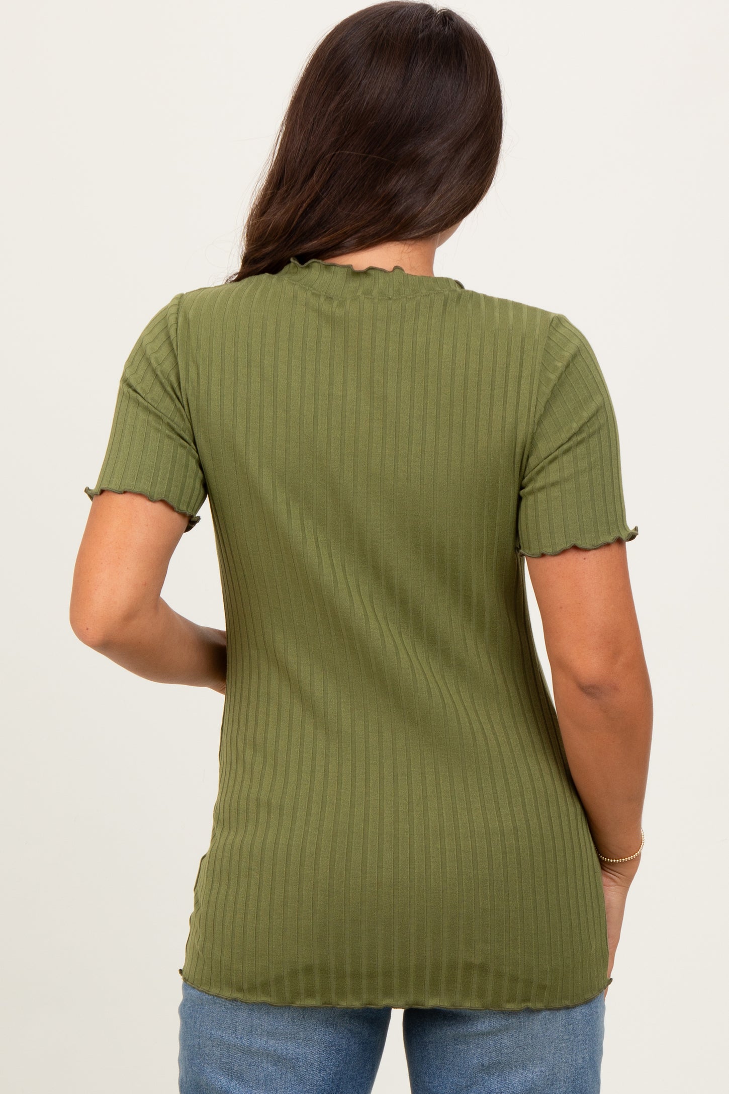 woman wearing a green ribbed maternity top with short sleeves and scalloped edges