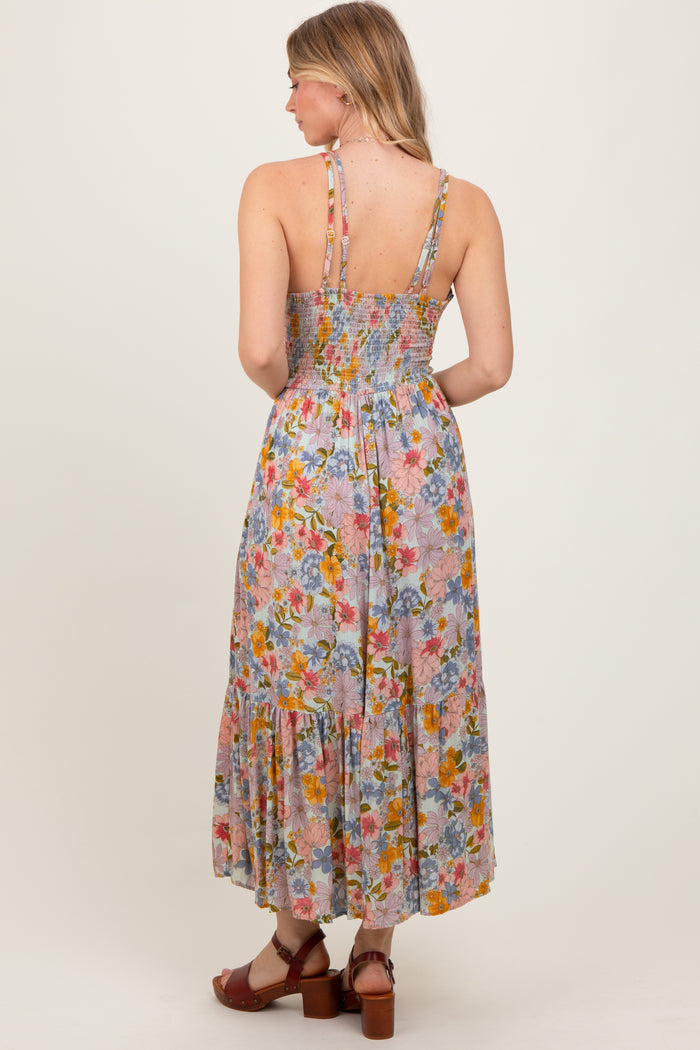 woman wearing a floral maxi dress with a smocked back and tiered hem, showing the back view