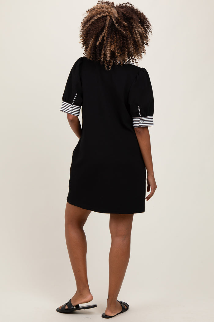 woman wearing a black maternity dress with striped short sleeves, standing with her back to the camera