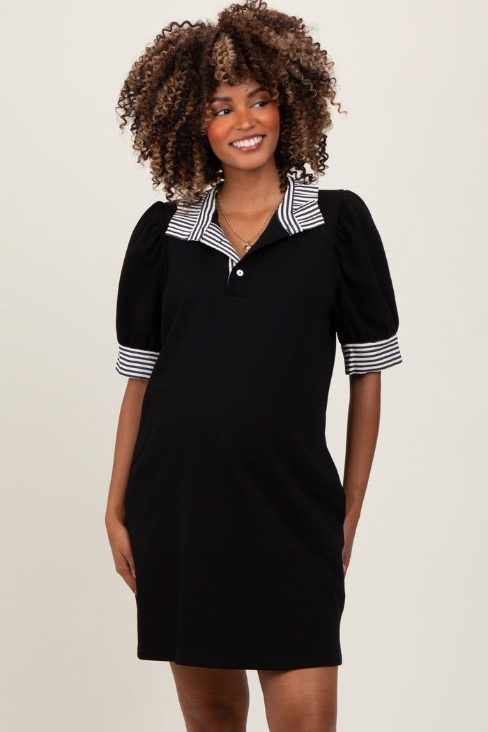 woman wearing a black maternity polo dress with stripe puff sleeves and a buttoned collar, smiling and showing her baby bump