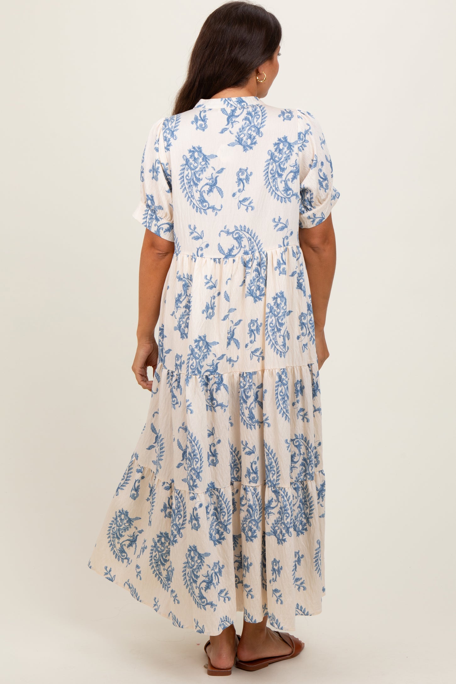 woman wearing a white and blue floral print maternity maxi dress with short sleeves and a tiered skirt