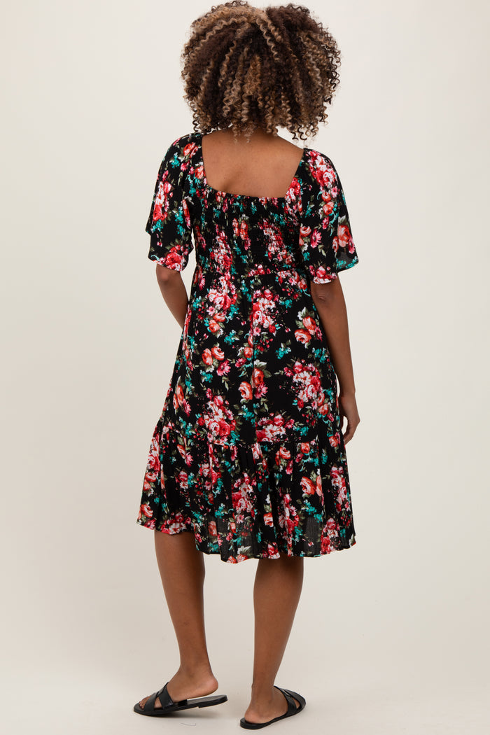 woman wearing a black floral maternity dress with short sleeves and a flared hem