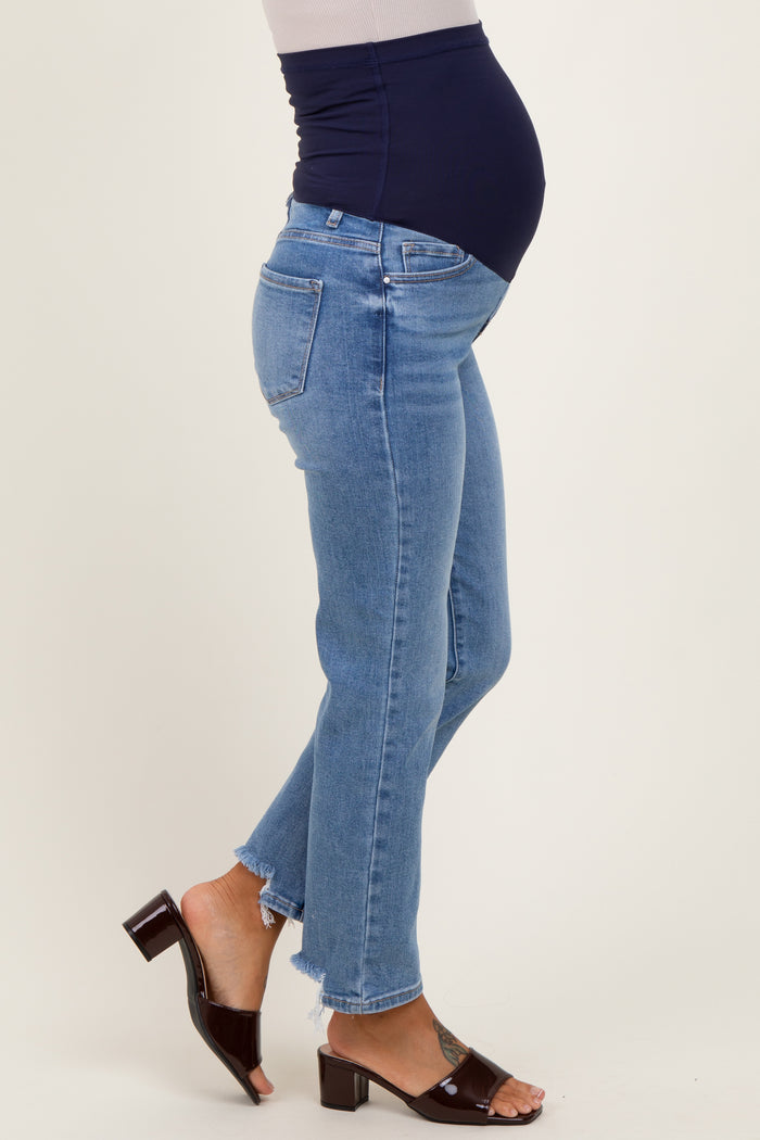 woman wearing blue maternity jeans with a frayed hem and a navy maternity top, showing her baby bump