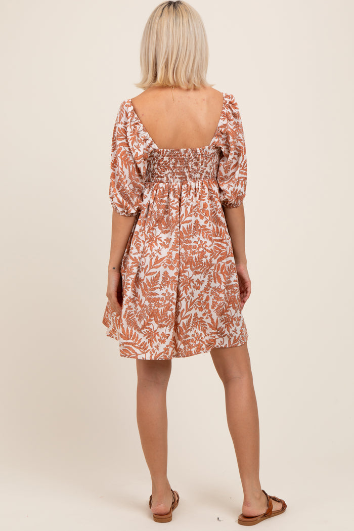 woman wearing a backless floral print maternity dress with puff sleeves and a smocked bodice
