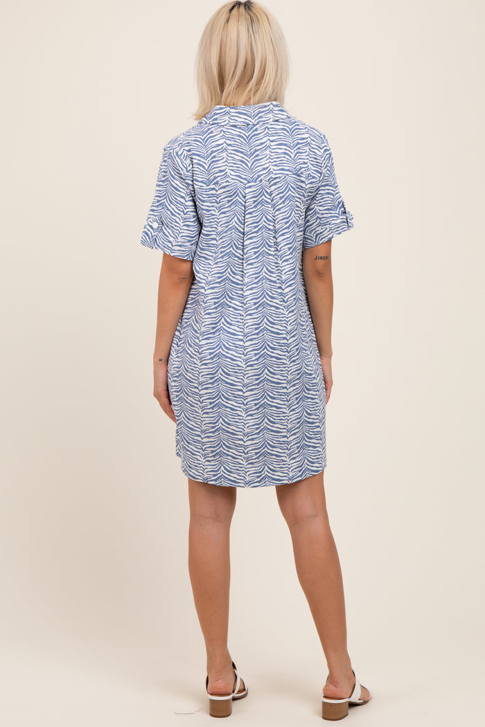 woman wearing a blue and white patterned maternity dress standing with her back to the camera