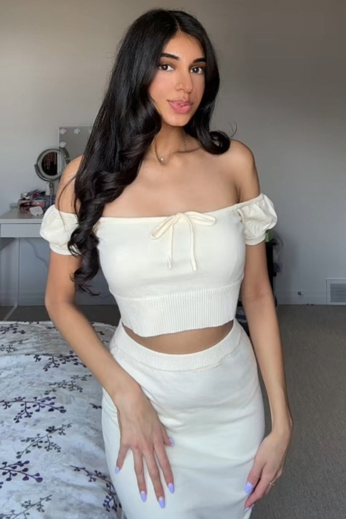 woman wearing an off-white off-the-shoulder crop top with puff sleeves and a matching cut-out midi skirt
