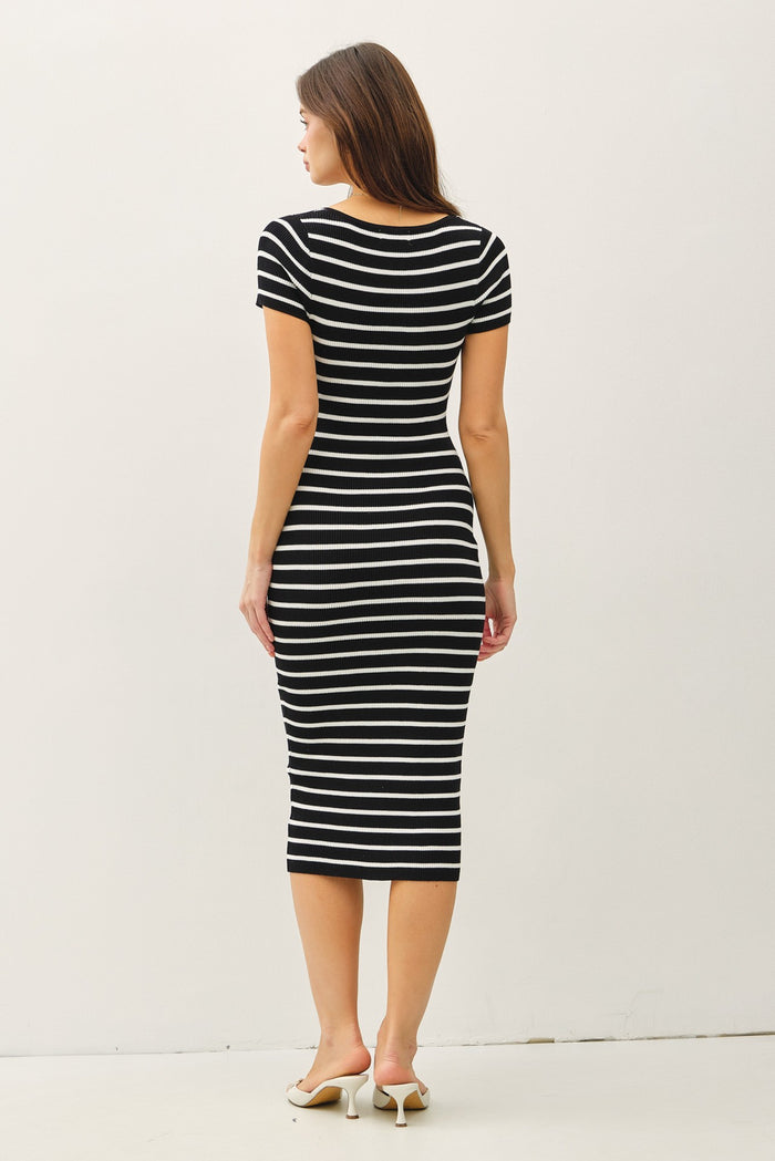 woman wearing a black and white striped fitted midi dress while standing with her back to the camera