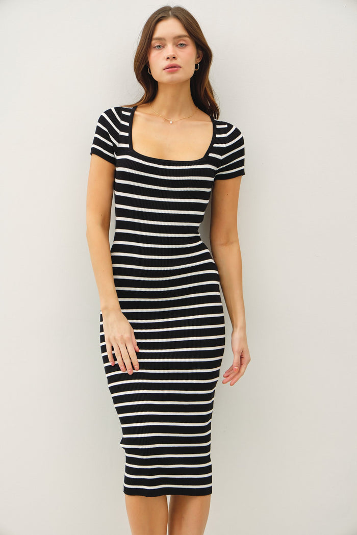 woman wearing a black and white striped fitted midi dress with short sleeves and a square neckline