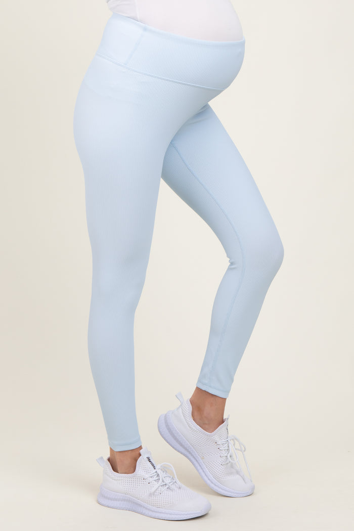 woman wearing light blue maternity leggings with a supportive belly band and white athletic shoes, showing baby bump