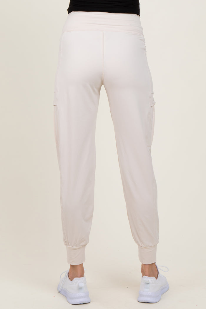 woman wearing light pink maternity cargo pants, showing the back view with elastic waistband and cuffed hems
