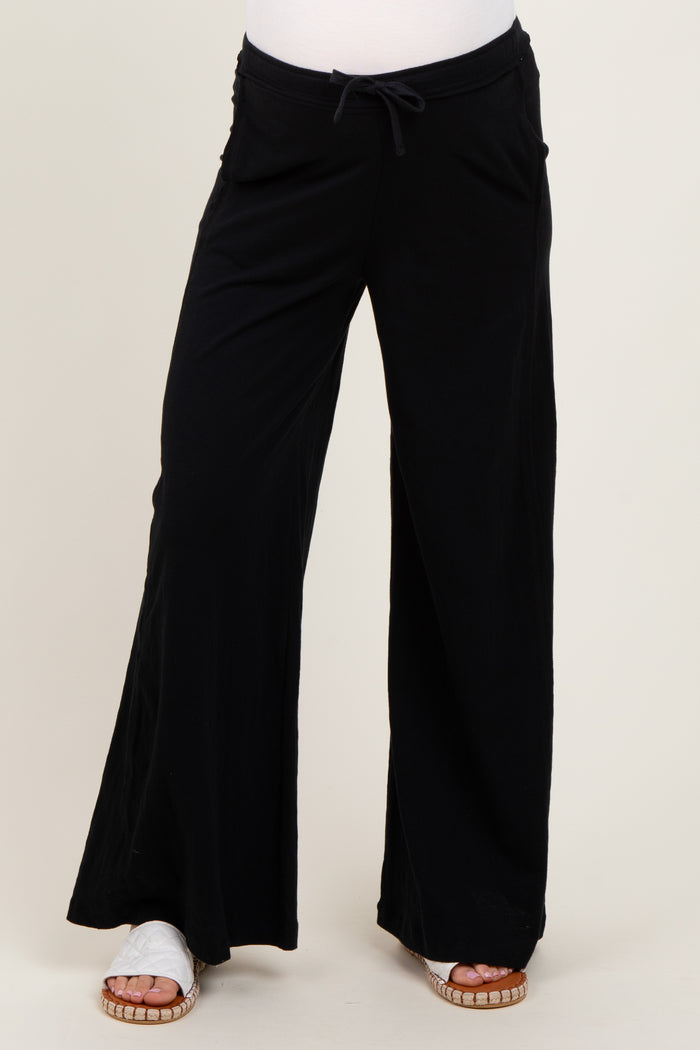 woman wearing black wide-leg maternity pants with side pockets and a drawstring waistband