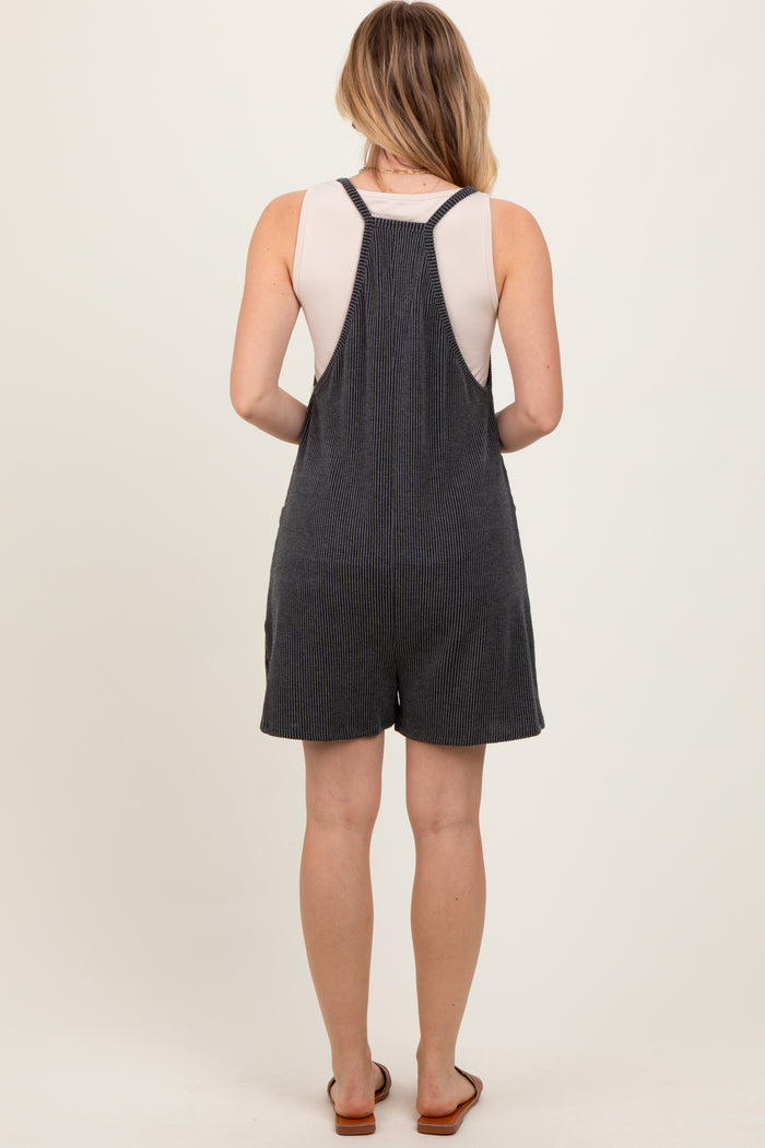 woman wearing a gray striped overall romper with a sleeveless top and back straps, standing with her back to the camera