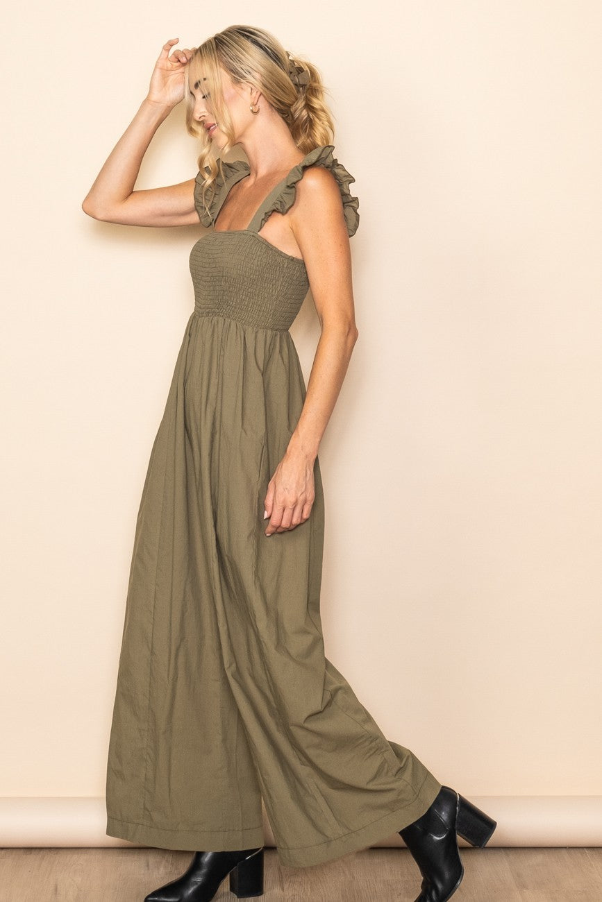 woman wearing an olive green maxi dress with ruffled sleeves and a fitted bodice, posing sideways with black ankle boots