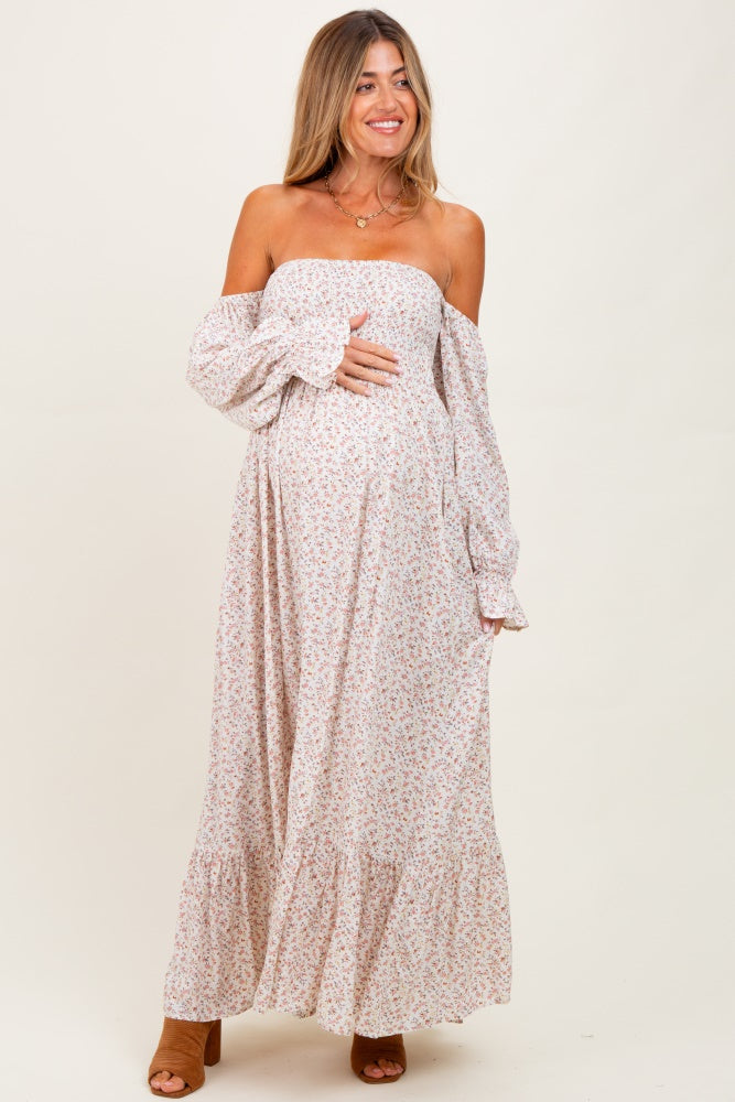 woman wearing a light pink off-the-shoulder floral maternity dress with long sleeves and a baby bump visible