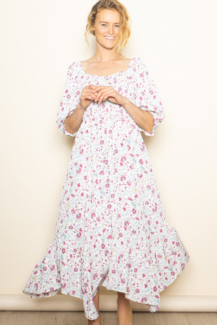 woman wearing a white floral maxi dress with a square neckline and three-quarter sleeves