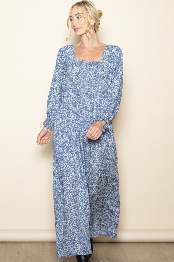 woman wearing a long blue floral maxi dress with long sleeves and a square neckline