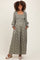 woman wearing a green floral maternity maxi dress with long sleeves and pockets, showing her baby bump