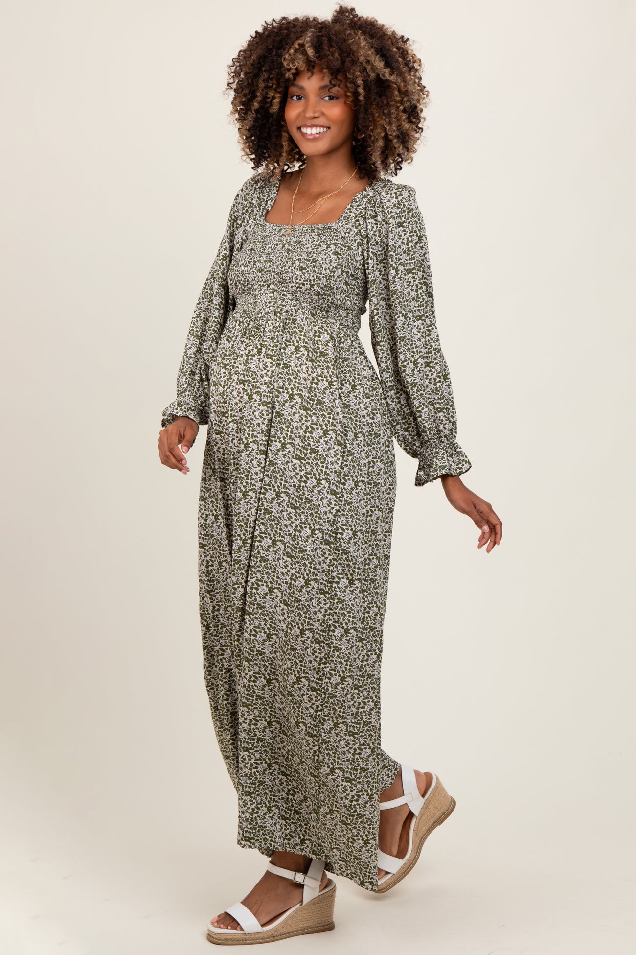 woman wearing a green floral maternity maxi dress with long sleeves and a baby bump visible