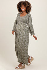 woman wearing a green floral maternity maxi dress with long sleeves and a baby bump visible