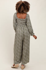 woman wearing a floral print maternity jumpsuit with a smocked back and long sleeves, showing her baby bump from the side