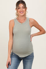 woman wearing a light green maternity tank top and showing off her baby bump while posing with a smile