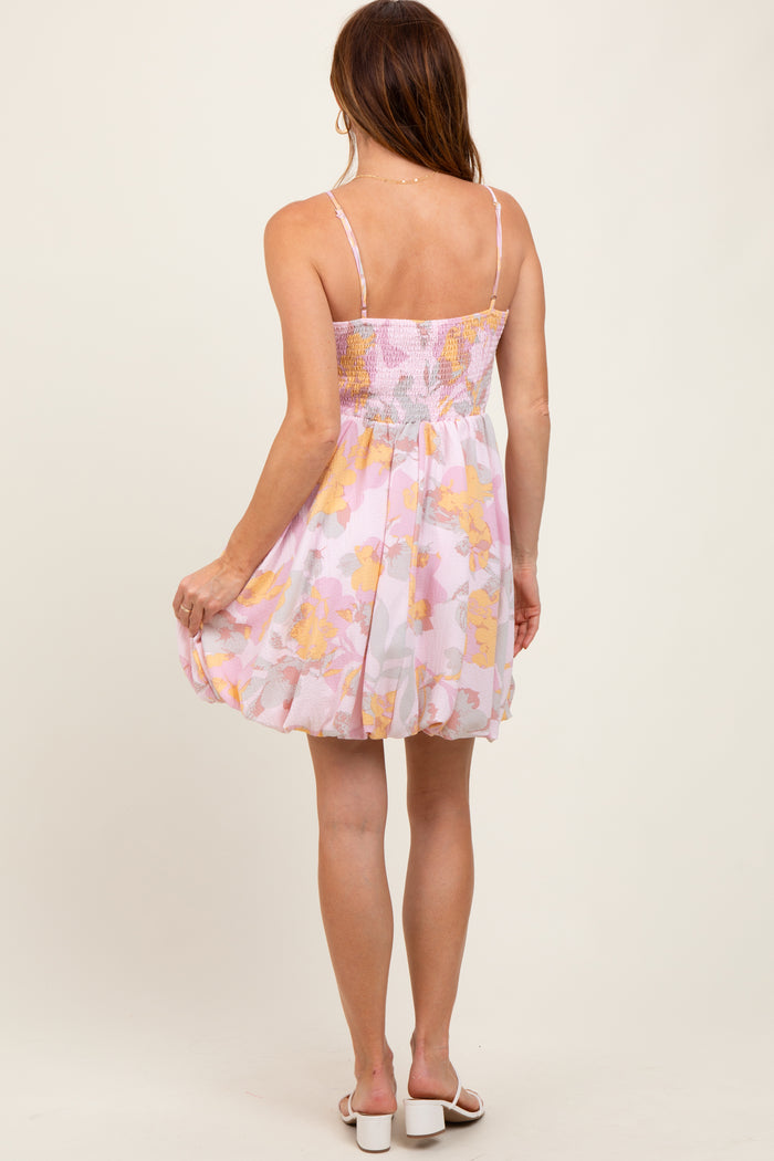 woman wearing a floral pink and yellow sundress with a fitted bodice and flared skirt, showing the back view