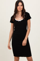 woman wearing a black short sleeve dress with a white bow detail at the neckline