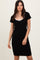 woman wearing a black short sleeve dress with a white bow detail at the neckline