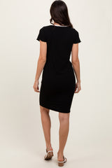 woman wearing a black short sleeve fitted dress seen from the back, styled with flat sandals