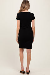 woman wearing a black short sleeve fitted maternity dress, standing with her back to the camera