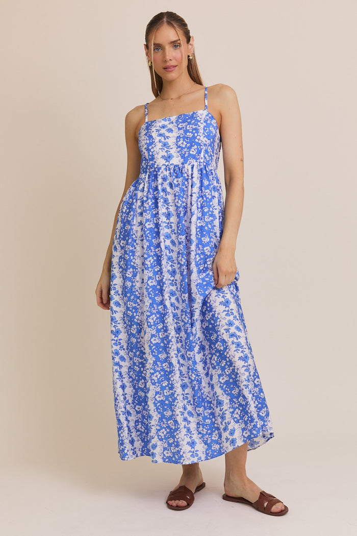 woman wearing a blue and white floral maxi dress with thin straps and a loose fit