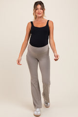 woman wearing a black maternity tank top and beige maternity flared leggings, showcasing her baby bump
