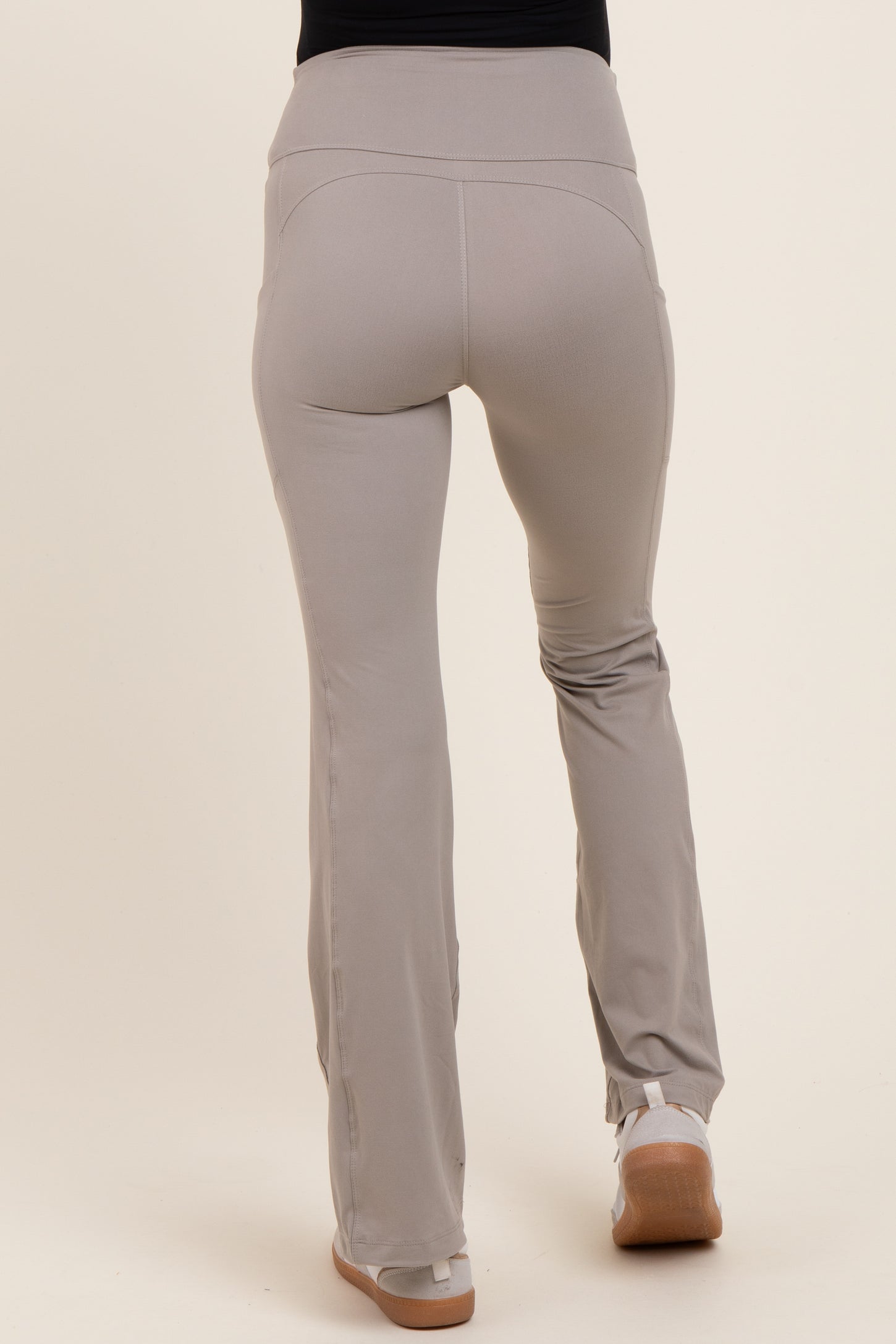woman wearing light grey maternity leggings with a high waistband and flared bottom, seen from the back