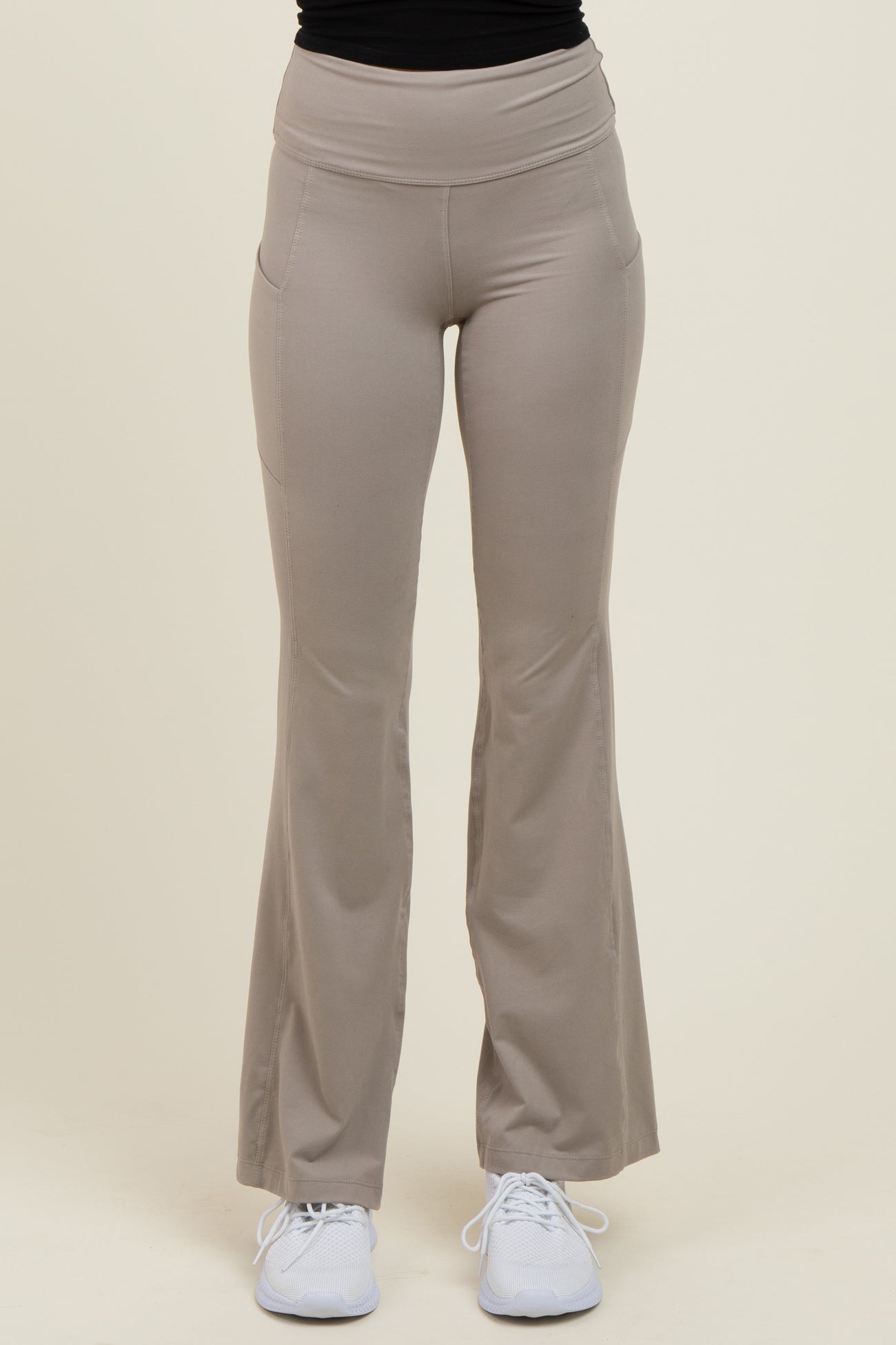 woman wearing light taupe flared yoga pants with a high waistband and side pockets