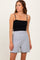 woman wearing a black fitted tank top and gray high-waisted shorts with scalloped edges
