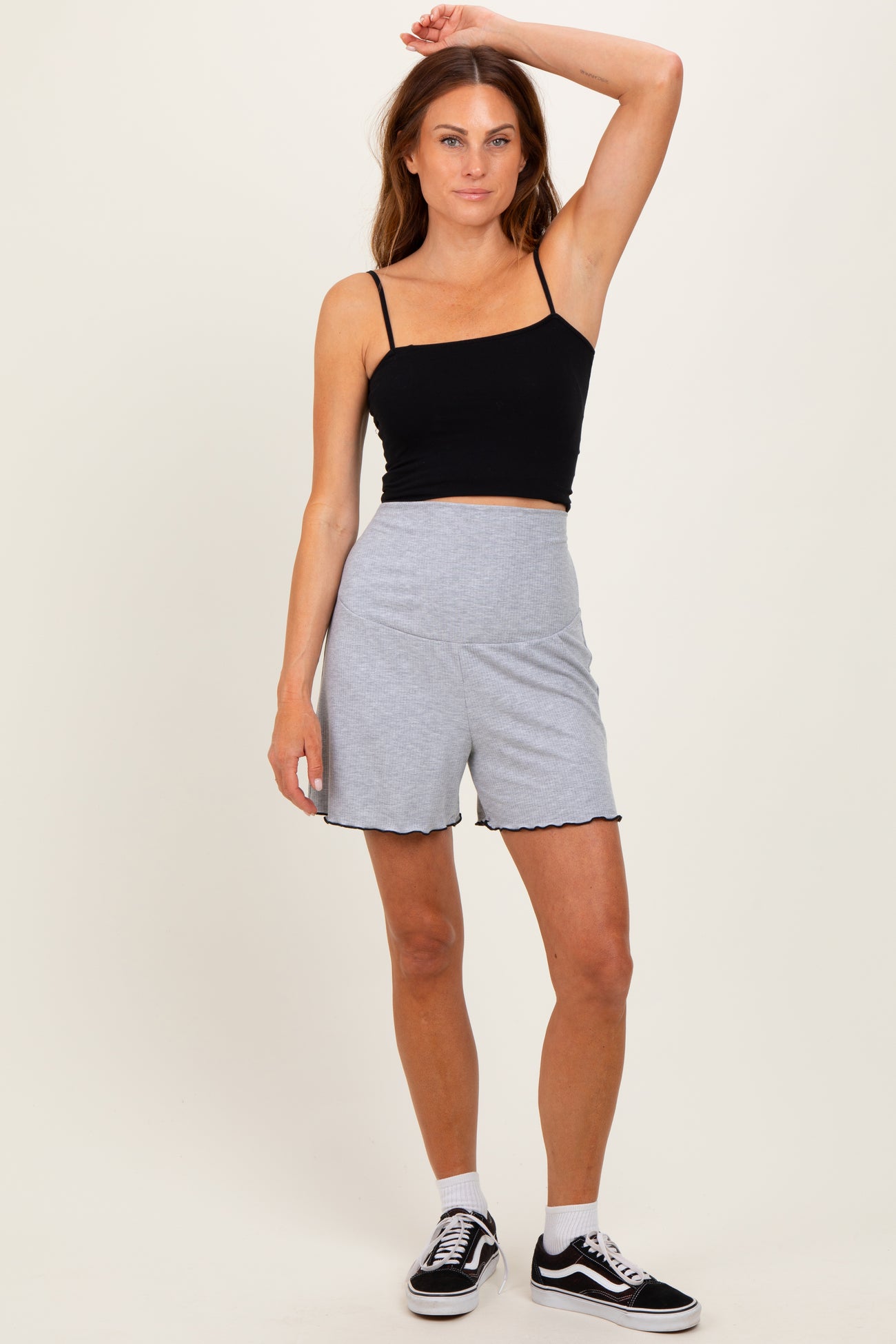 woman wearing a black cropped tank top and gray scalloped hem shorts