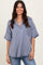 woman wearing a blue striped oversized short sleeve top with a v-neck and front pocket