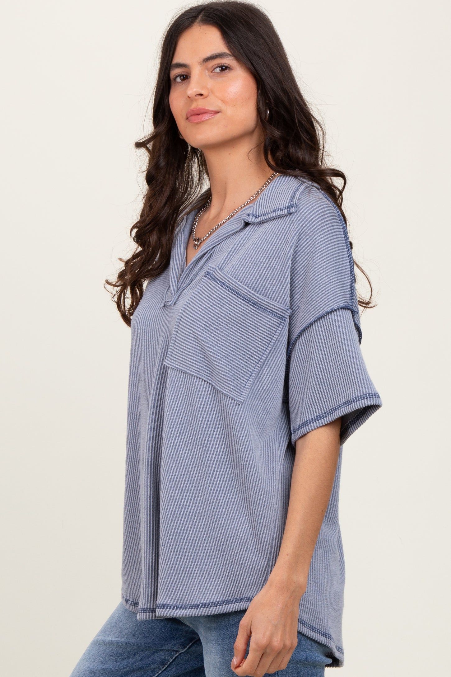 woman wearing a blue striped oversized short sleeve top with a front pocket and a relaxed fit