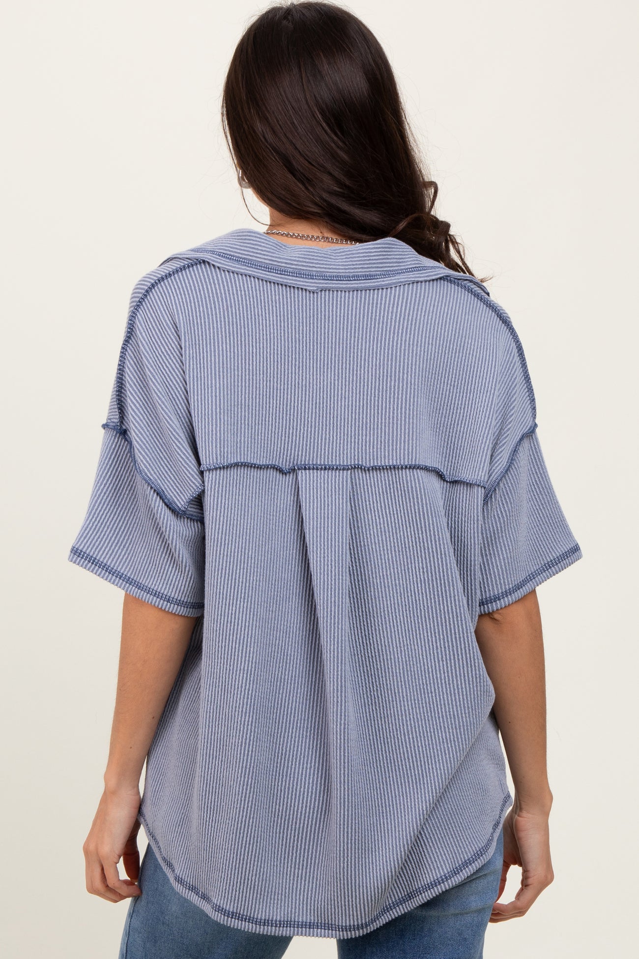 woman wearing a blue and white striped oversized shirt with a relaxed fit and back seam details