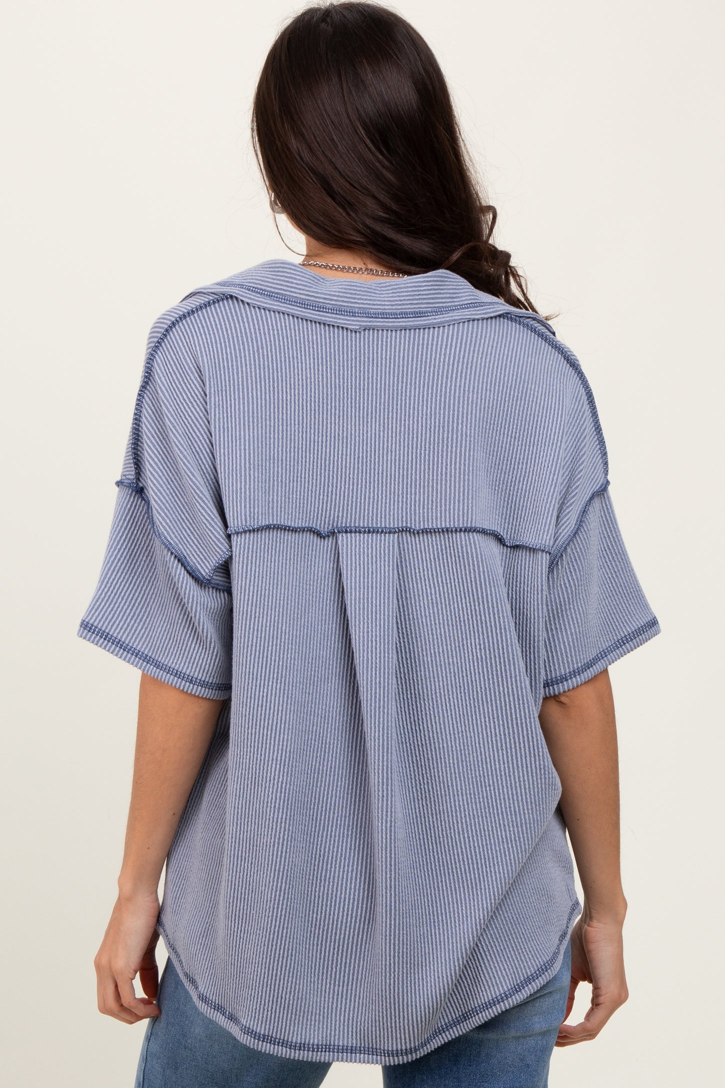 woman wearing a blue and white striped oversized shirt with a relaxed fit and back seam details