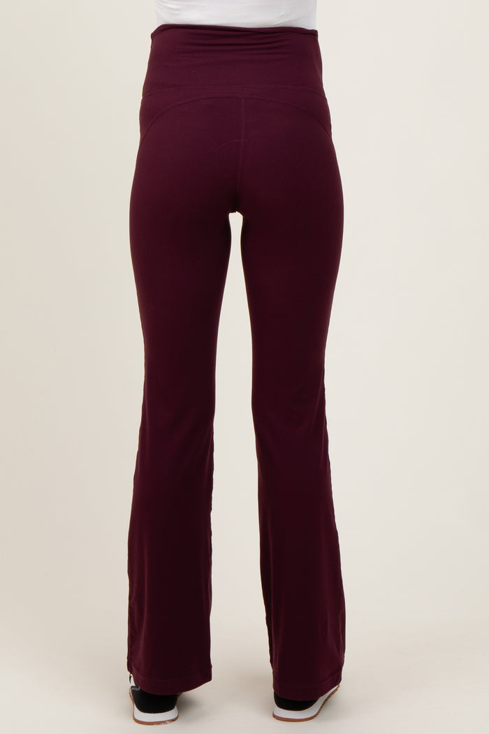 woman wearing maroon maternity flared yoga pants, shown from the back with a high waistband