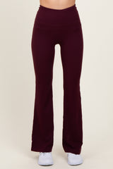 woman wearing burgundy flared workout leggings with a high waistband and paired with white athletic shoes